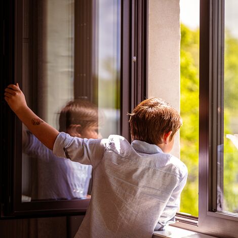 Boy looking out of open window.