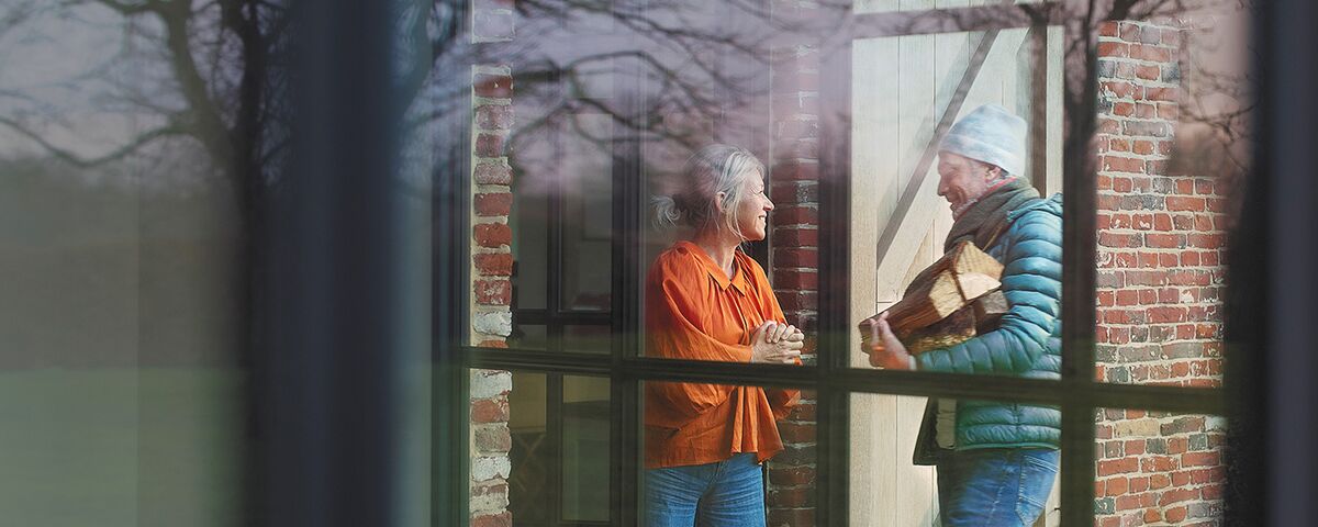 Woman and man talking outside next to large Reynaers Aluminium window.
