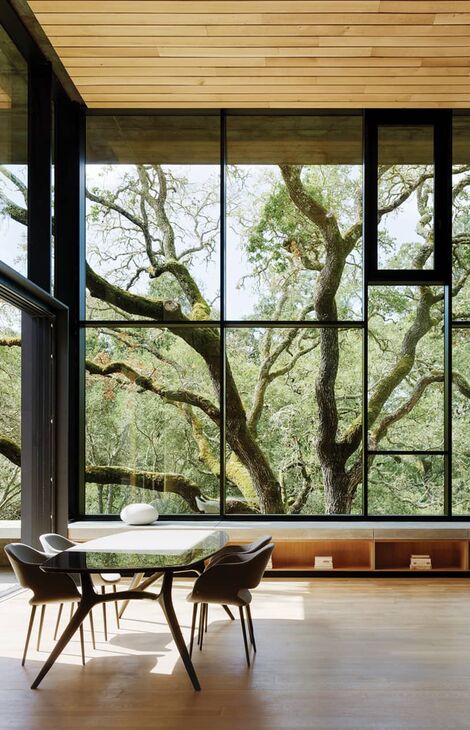 Interior view of The Giving Tree private project. A modern table is set in front of big glass surfaces.